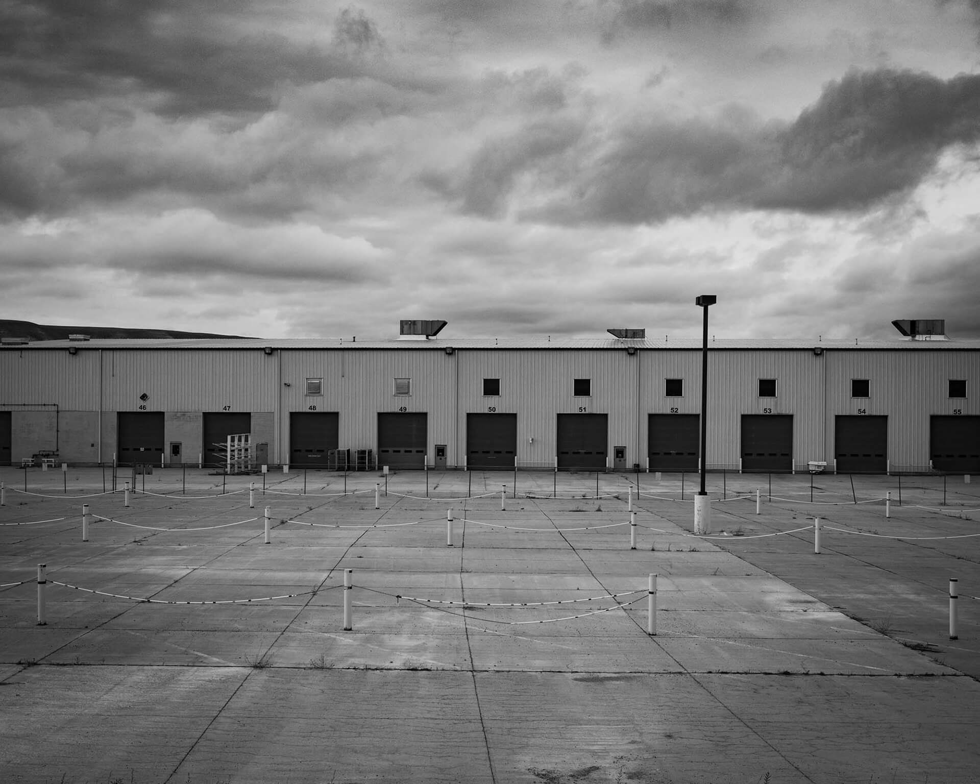 a deserted loading dock with a strip of loading bays beneath a dramatic cloudy sky