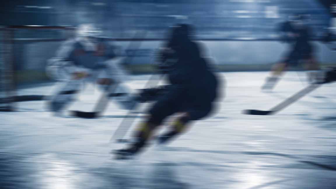 Ice Hockey Arena: Professional Forward Player Breaks Defense, Prepairing to Shoot Puck with Stick to Score Goal. Two Competitive Teams Play Intense Game.