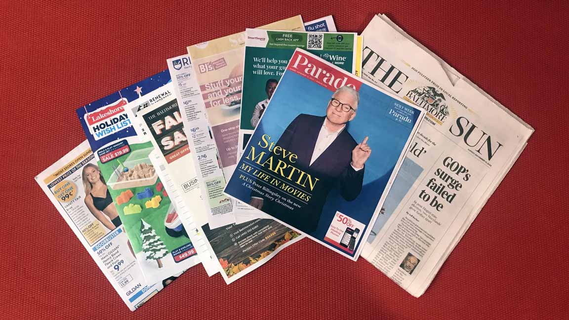 AN image of the SUnday Nov 13, 2022 Baltimore Sun newspaper with its inserted supplements of ads and coupons for products along with the Parade magazine insert with Steve Martin on the cover