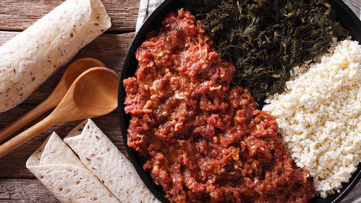 Ethiopian cuisine: kitfo with herbs and cheese on a plate and injera. Horizontal view from above