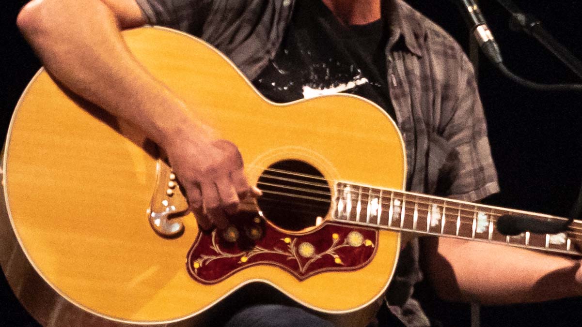 A photo of Eddie Vedder playing guitar, cropped to just the guitar and his hands