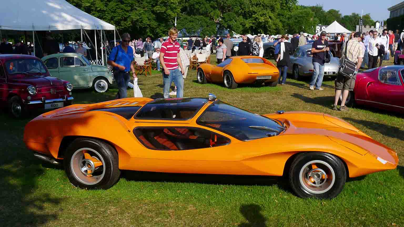 The Probe at an auto show, on a green lawn, surrounded by people and other old collectible cars.