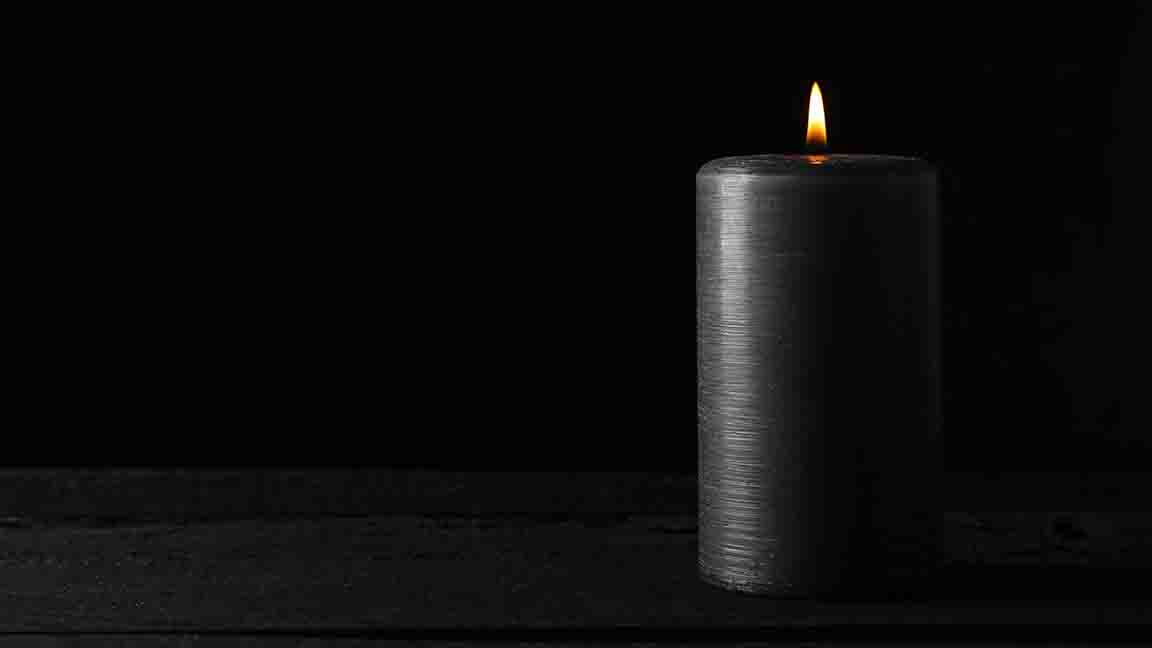 Candle on wooden table against black background